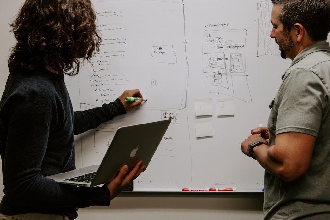 people drawing on a white board